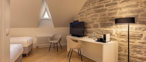 A cozy room with a loft bed, a desk with a computer, a chair, and a lamp.