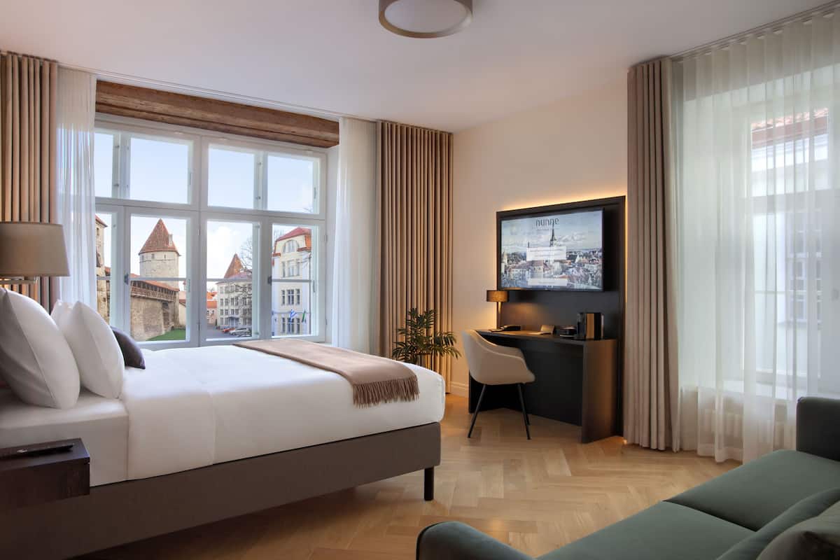Ein Hotelzimmer mit einem großen Bett, einem Schreibtisch, einem Fernseher und Blick auf die Stadt.