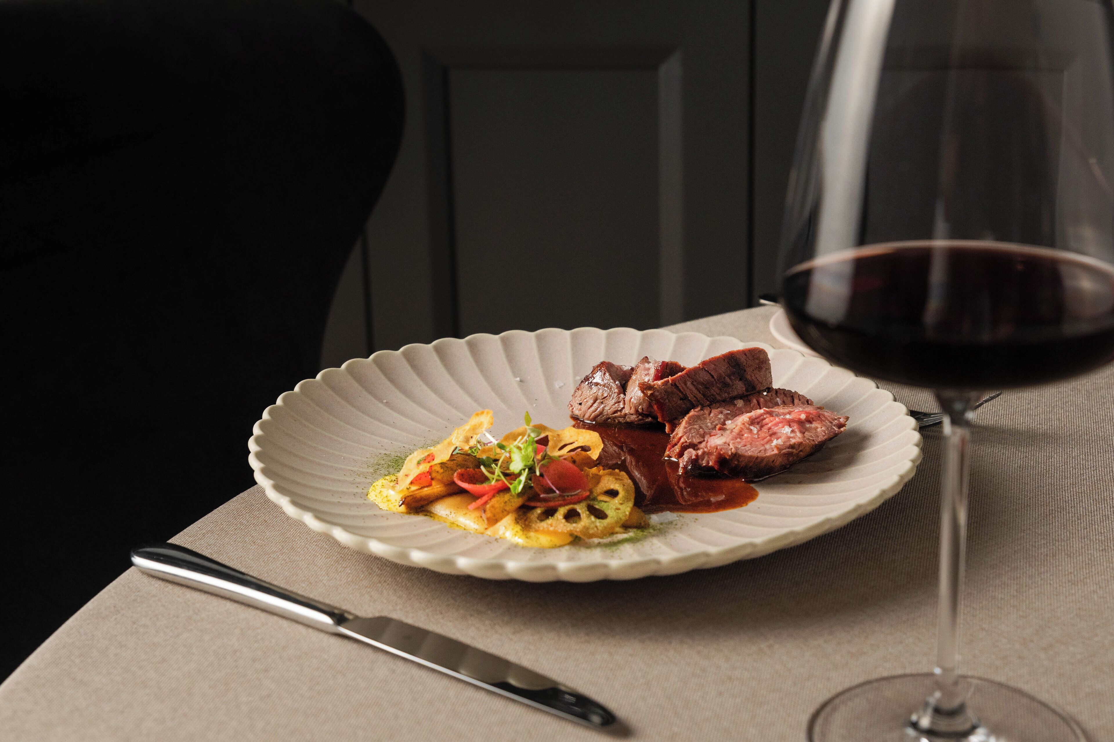 A plate of food with a glass of red wine on a table.