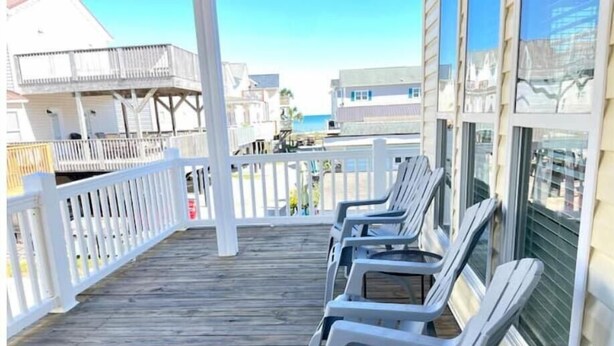 A wooden deck with white railings and several white plastic chairs. - Sea Breeze Retreat with Gorgeous Ocean Views! (Myrtle Beach)