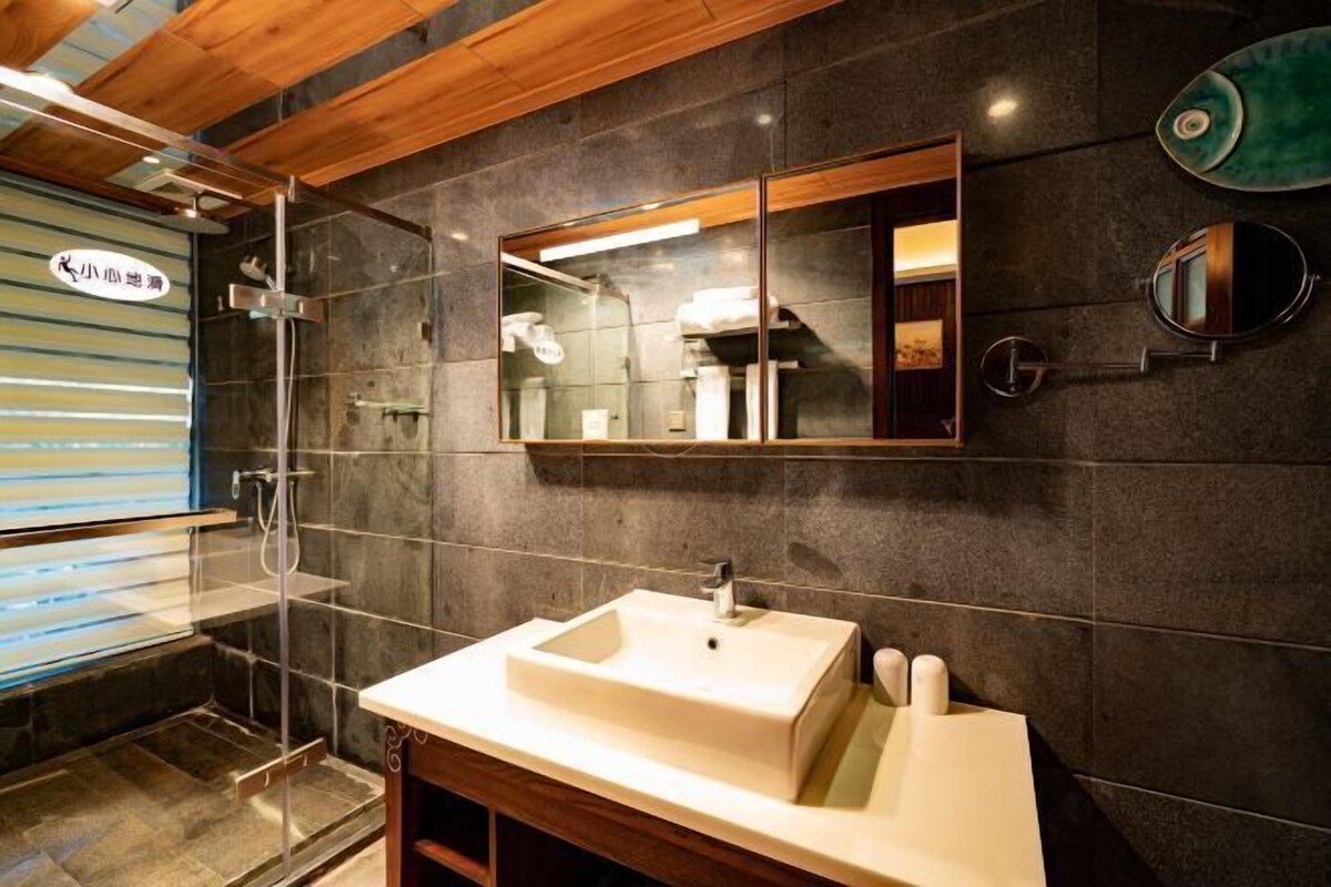 A modern bathroom with a large mirror, a sink, and a shower area.