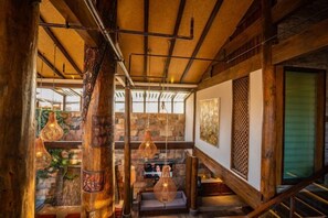 A wooden interior with a staircase, hanging lights, and a stone wall. - Shuhe Yuannian Holiday Courtyard (Lijiang)