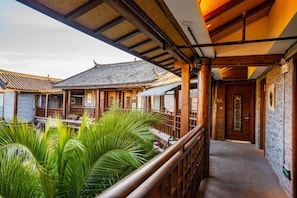 A traditional building with a covered walkway, wooden railings, and a door with a decorative glass panel. - Shuhe Yuannian Holiday Courtyard (Lijiang)