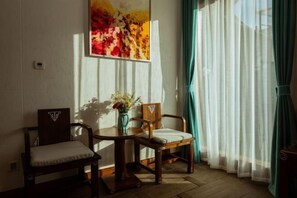 A room with two wooden chairs, a small table, and a vase with flowers. - Shuhe Yuannian Holiday Courtyard (Lijiang)