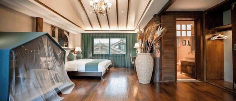 Una habitación con una cama, un jarrón grande y vistas a un edificio tradicional a través de una ventana.