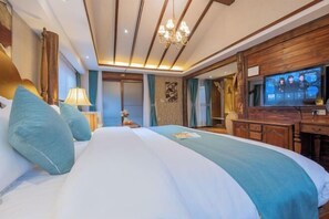 A hotel room with a large bed, a desk with a television, and a chandelier. - Shuhe Yuannian Holiday Courtyard (Lijiang)