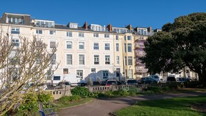 A row of townhouses with a paved path and a bench in the foreground.