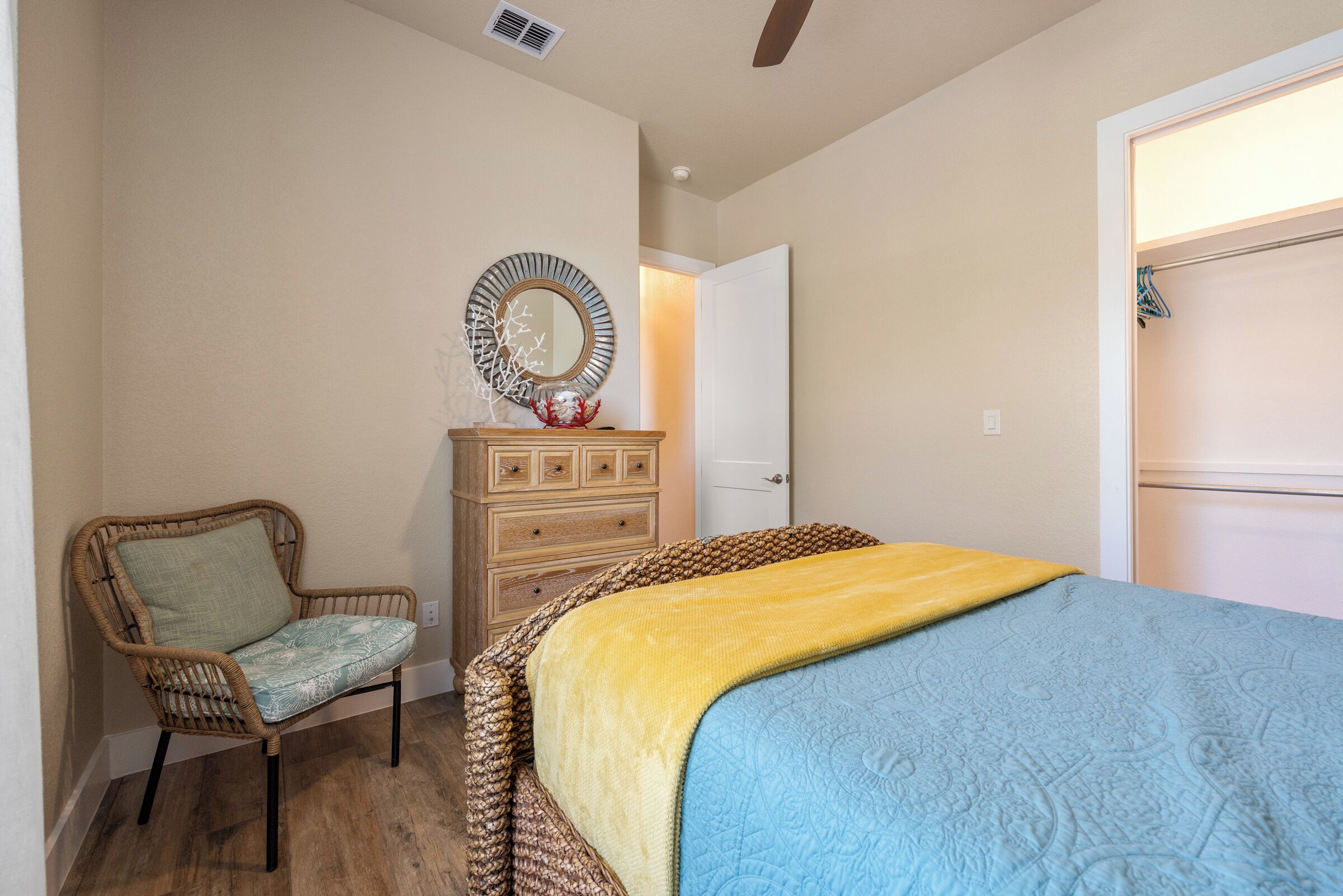 A bedroom with a bed, a chair, a dresser, and a mirror.