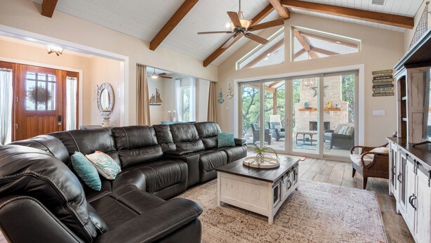 A spacious living room with a black leather sectional sofa, a white coffee table, and a ceiling fan. - Outdoor Sanctuary/Lake View/Hot tub & Game Room! (Canyon Lake)