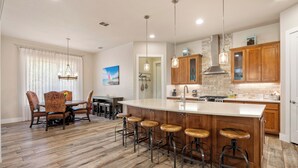 A modern kitchen with a large island, bar stools, wooden cabinets, and pendant lighting. - Outdoor Sanctuary/Lake View/Hot tub & Game Room! (Canyon Lake)
