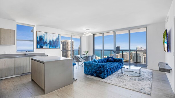 A modern apartment with a kitchen, dining area, and living room with a large window overlooking a cityscape.