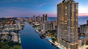 A high-rise hotel with multiple floors, a swimming pool, and a waterfront view.