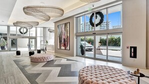 A spacious lobby with large windows, a modern chandelier, and a large wreath decoration.