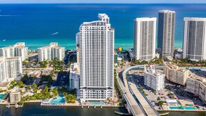A high-rise hotel with a view of the ocean, a marina, and a bridge.