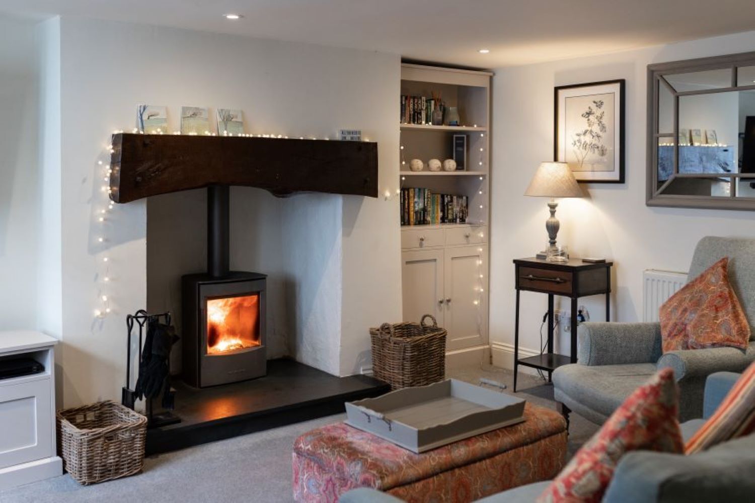 A cozy living room with a wood-burning stove, a bookshelf, a lamp, and a comfortable seating area.
