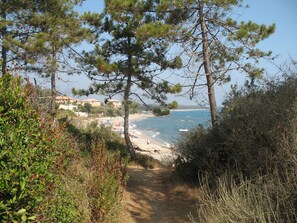A coastal path leading to a beach with umbrellas and people. - Mini-villa with direct access to the sea (150 m), courtyard, Wi-Fi, parking, enclosed garage (Linguizzetta)
