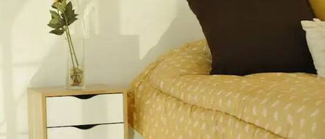 Un dormitorio con cama, una mesita de noche con un florero y un interruptor de luz en la pared.
