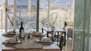 A dining area with a table set for two, large windows offering a view of a mountainous landscape.