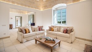Un salon spacieux avec deux canapés beige, une table basse en bois et une grande fenêtre qui laisse entrer la lumière naturelle.