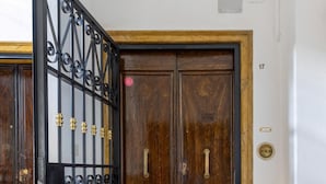 A wooden double door with brass handles and a black wrought iron gate with brass accents. - Irnerio Apts - Blue Velvet by Wonderful Italy (Bologna)
