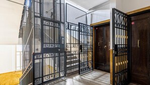 A hallway with a black metal gate, a wooden door, and a marble floor. - Irnerio Apts - Blue Velvet by Wonderful Italy (Bologna)