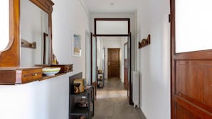 Passadís amb una porta de fusta, un radiador i una estant amb objectes decoratius.