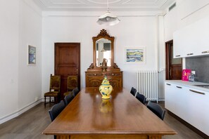 Ruokailuhuone, jossa on puinen pöytä, tuoleja, koristeellinen maljakko, peili ja patteri.