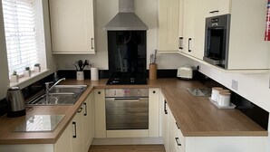 Une cuisine moderne avec des armoires blanches, des appareils en acier inoxydable et un plan de travail en bois.