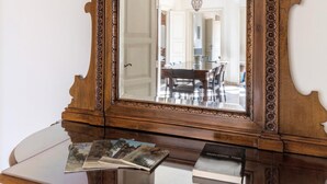 A wooden cabinet with a mirror, books, and a decorative base. - Irnerio Apts - Black Widow by Wonderful Italy (Bologna)
