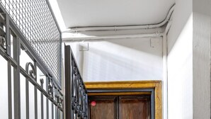 A hallway with a metal gate, a wooden double door, and a marble floor. - Irnerio Apts - Black Widow by Wonderful Italy (Bologna)