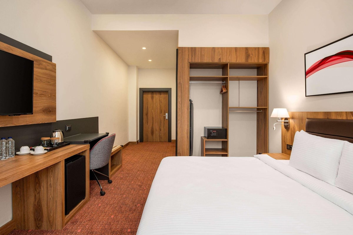 Une chambre d’hôtel comprenant un lit, un bureau avec une télévision, un four à micro-ondes et une armoire.