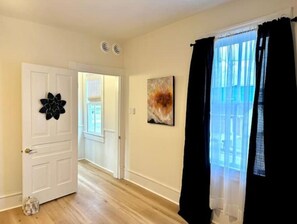 Cozy retreat with a door adorned with a decorative flower, a window with a view, and a beautiful painting above.