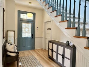 Enter a beautifully appointed entryway with a dark blue door, wooden bench, and console table.