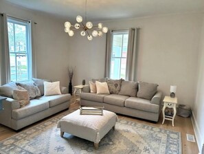Relax in this stylish living room with a large sofa, ottoman, and side table, perfect for unwinding with a view of the outdoors.
