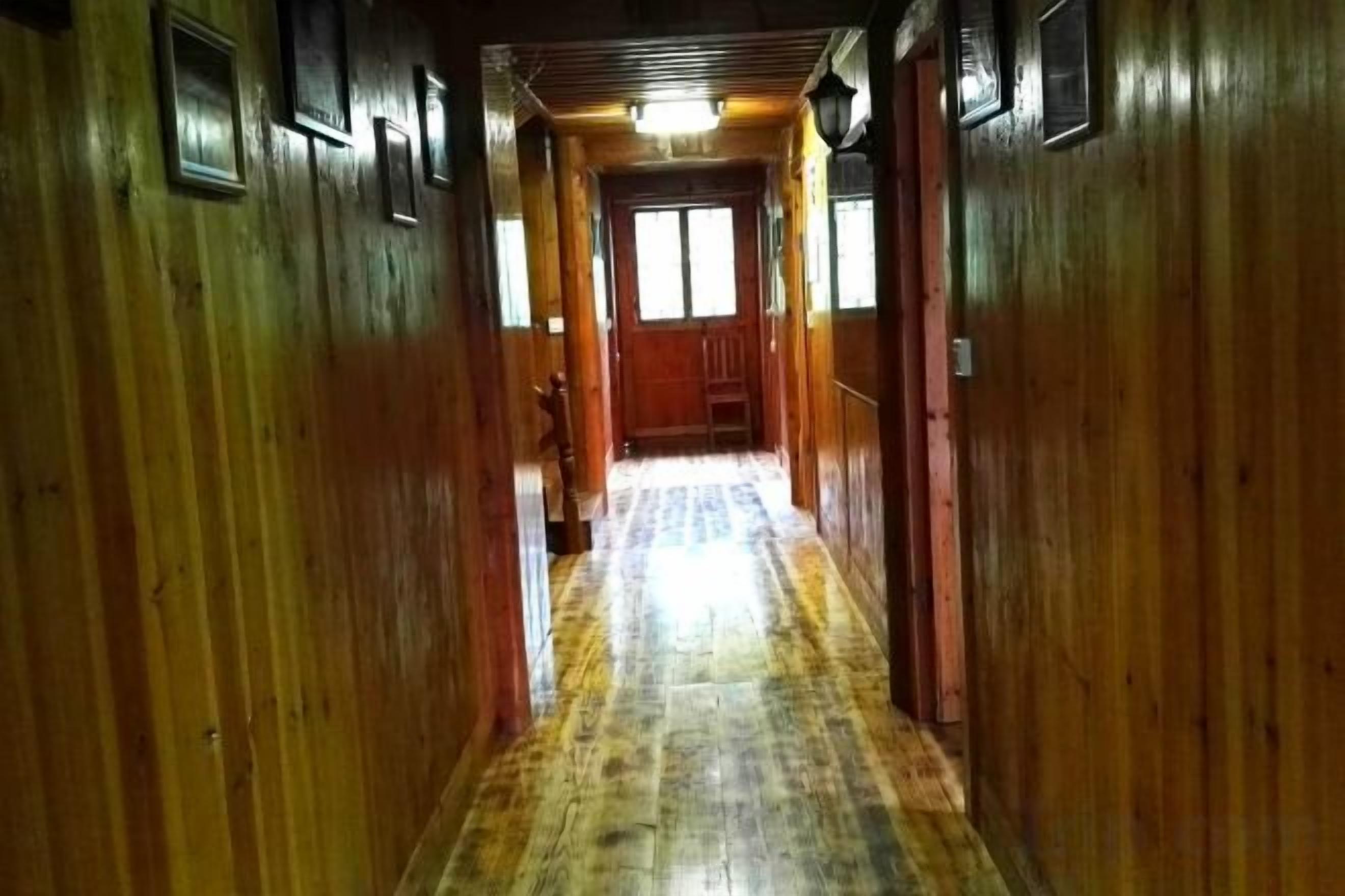 A wooden hallway with a wooden floor, doors, and a light fixture.
