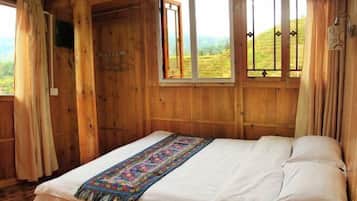 A wooden room with a bed, a window with curtains, and a view of the outdoors.