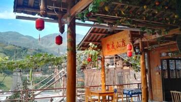 Una estructura de madera tradicional con un letrero, asientos al aire libre y vistas a las montañas.