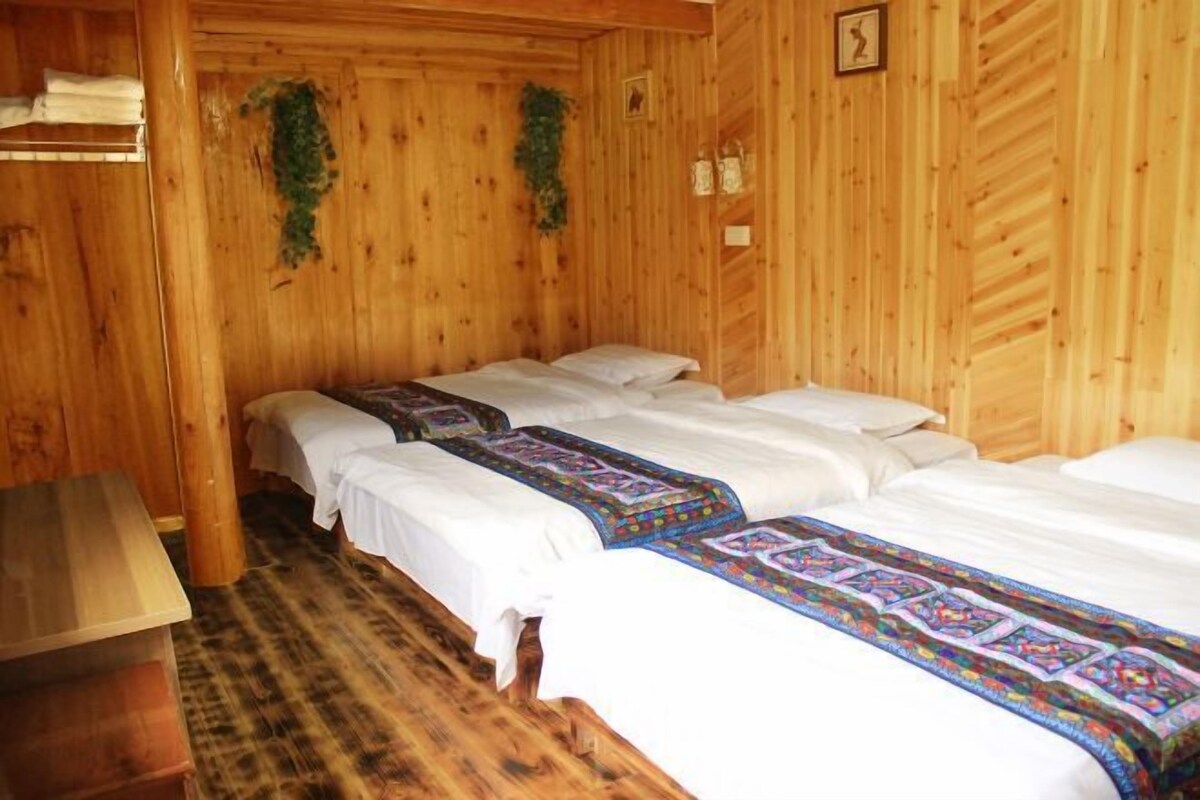 A wooden cabin room with three beds, a wooden bench, and a small table.