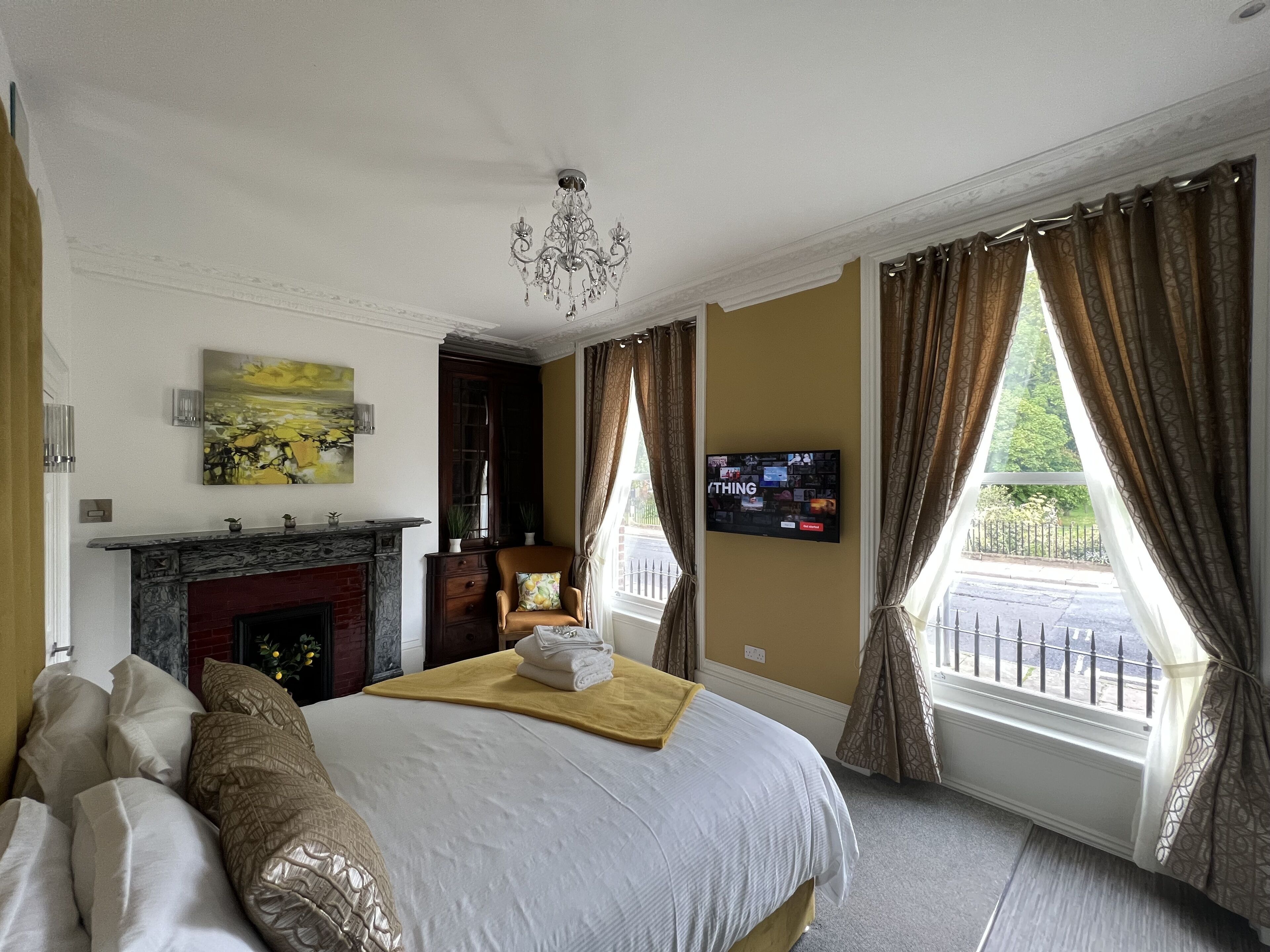 A hotel room with a bed, a fireplace, a TV, and a view of the outside.