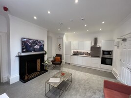 Una sala de estar moderna con chimenea, televisor, mesa de centro y una silla roja.