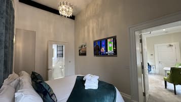 A hotel room with a bed, a television, and a chandelier.