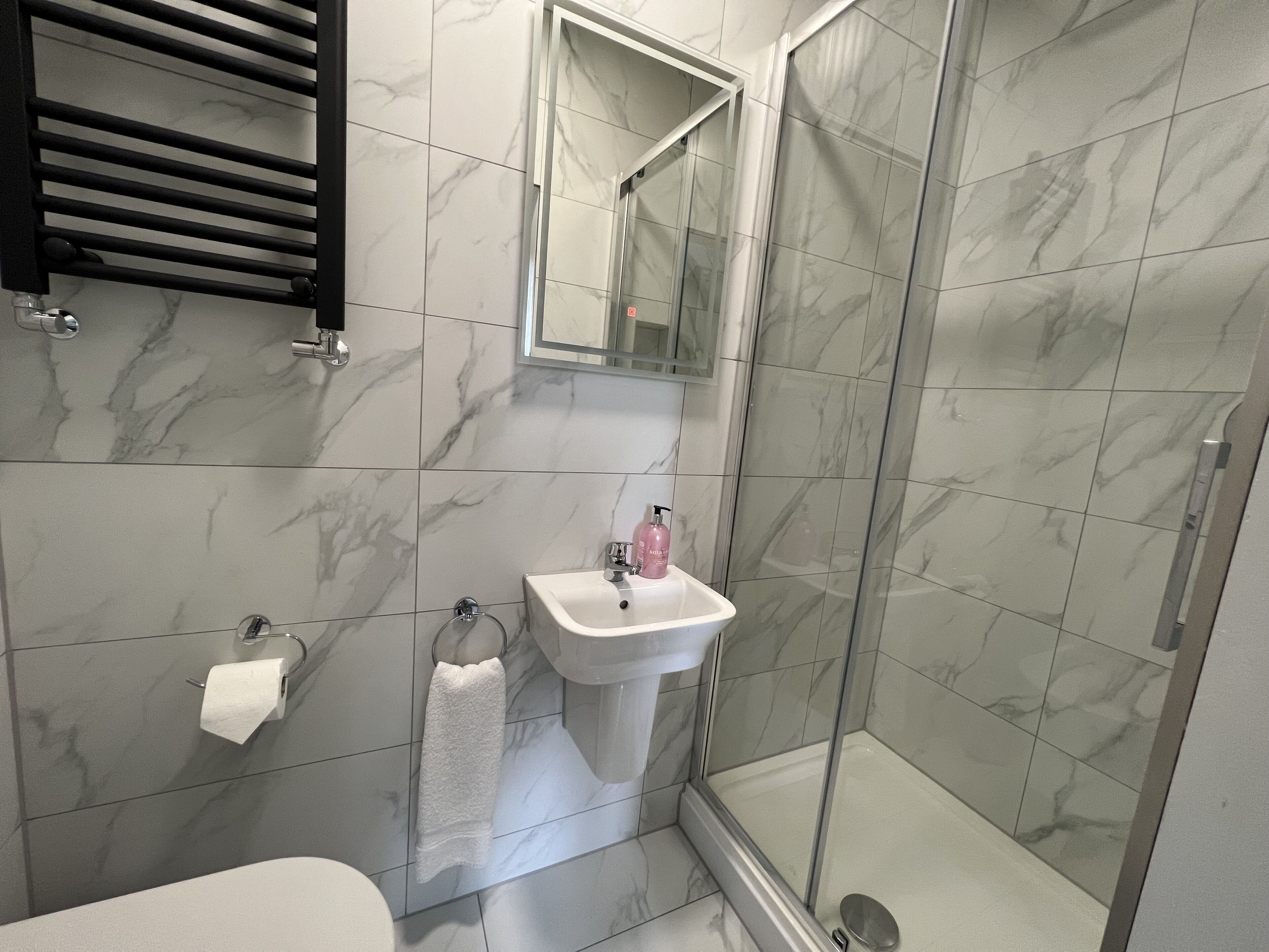 A bathroom with a shower, sink, and toilet.