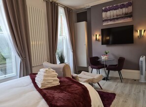 Ein Hotelzimmer mit einem Bett, einem Schreibtisch, zwei Stühlen, einem Fernseher und einer Heizung.