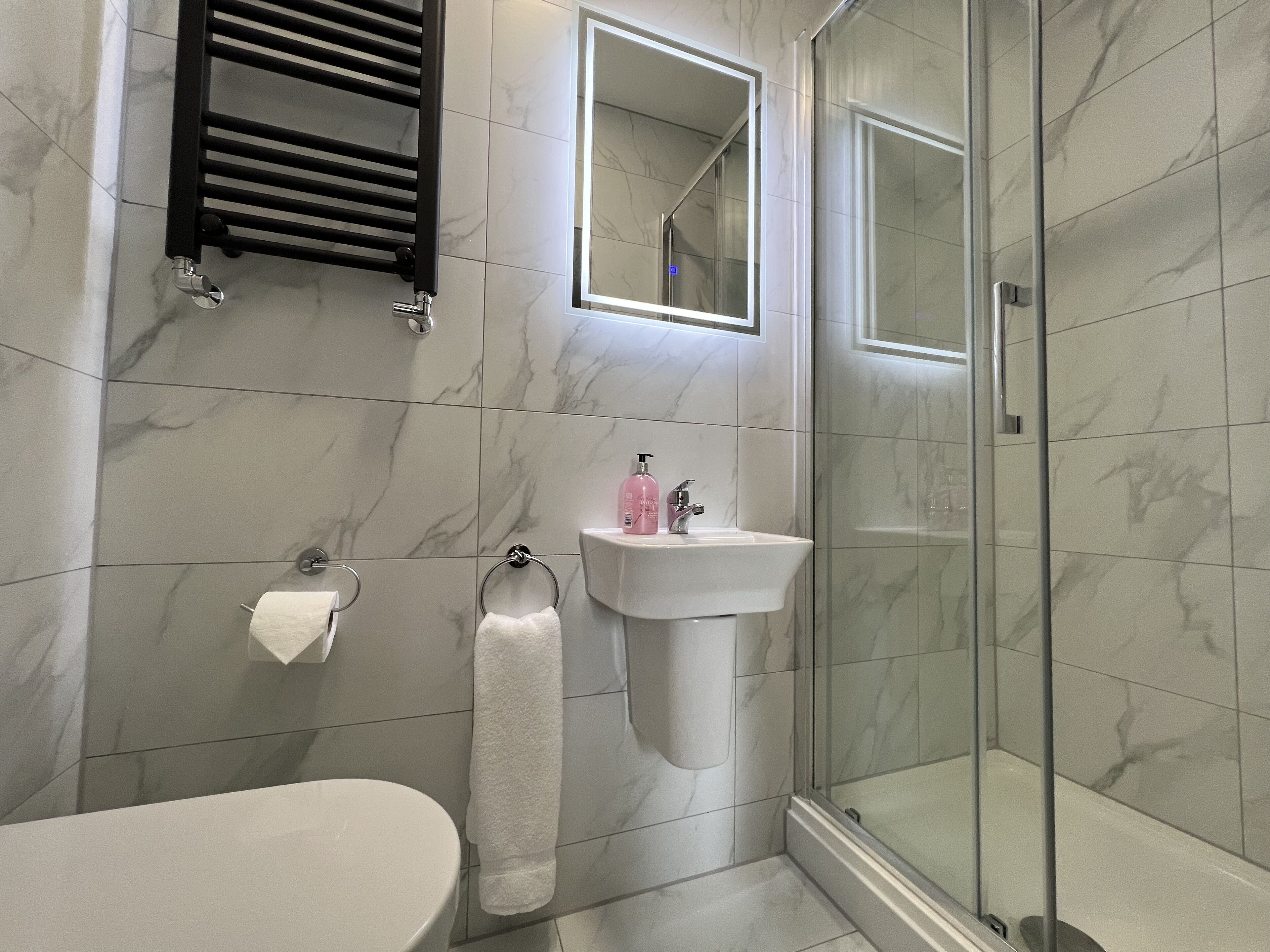Un baño moderno con inodoro, lavamanos y cabina de ducha de vidrio.