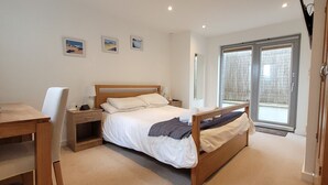 Makuuhuoneessa on sänky, yöpöytä, lamppu ja pieni työpöytä. Seinällä on kolme kehystettyä kuvaa.