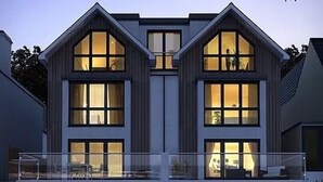 Moderni, kaksikerroksinen talo, jossa on suuret ikkunat ja parveke.