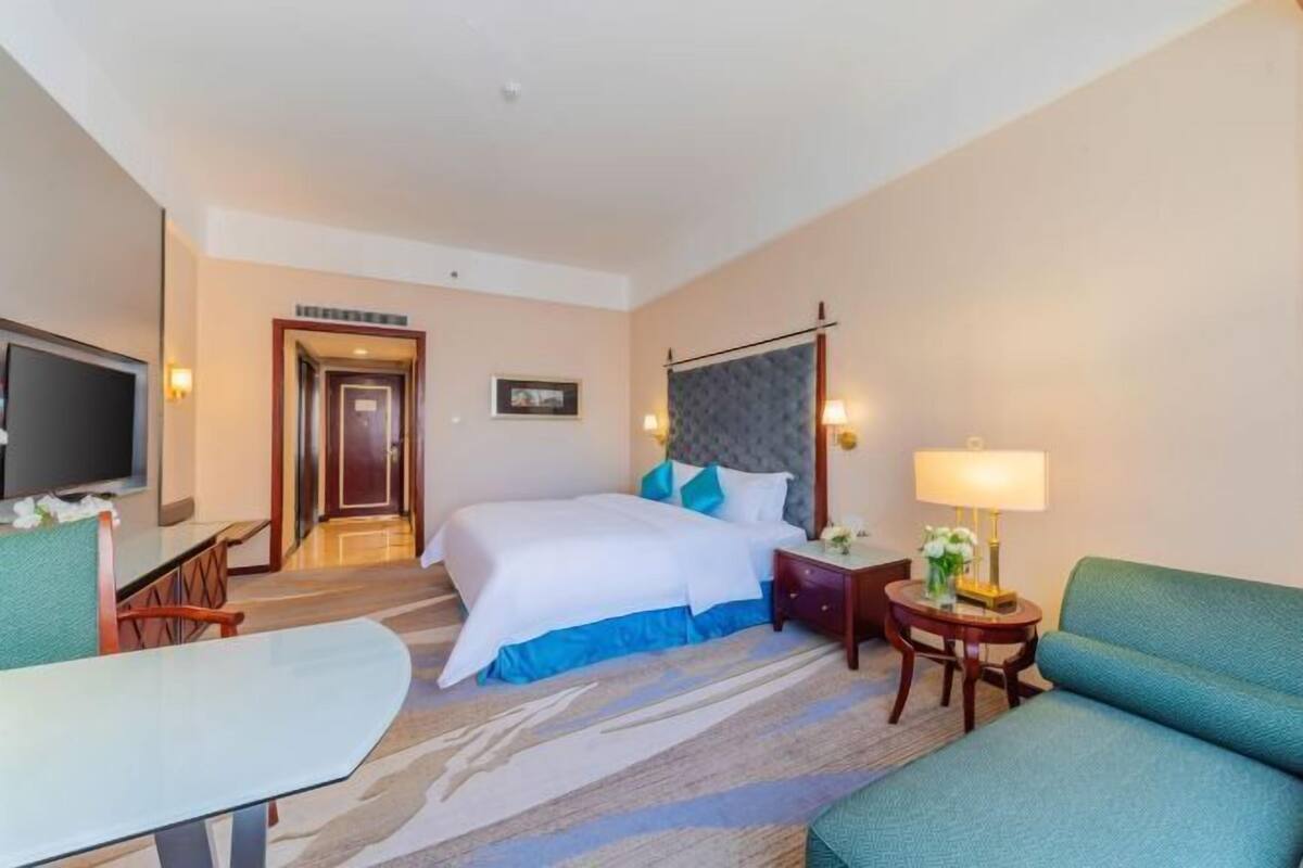 A hotel room with a bed, a TV, a desk, and a chair.