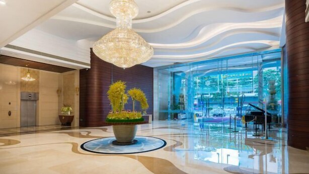 A spacious lobby with a modern chandelier, a large potted plant, and a glass facade offering a view of the outside. - Dongrong Hotel (Dongguan Municipal Government International Trade Center) (Dongguan)