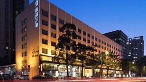A multi-story hotel with a modern facade, illuminated signage, and a street view with parked cars and trees. - Dongrong Hotel (Dongguan Municipal Government International Trade Center) (Dongguan)