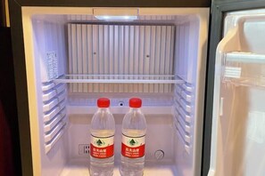 An open refrigerator with two bottles of water and a light on top. - Dongrong Hotel (Dongguan Municipal Government International Trade Center) (Dongguan)
